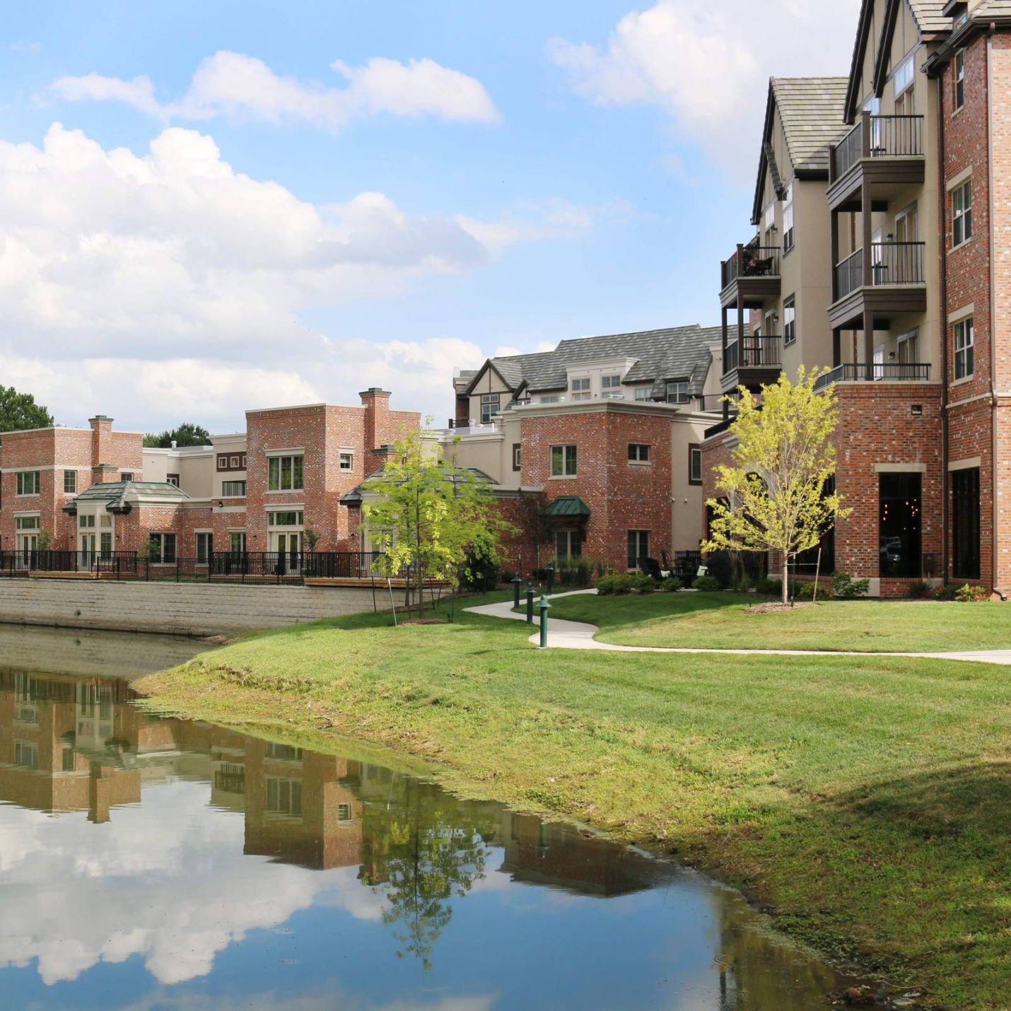 Mission 106 Luxury Apartments building exterior with a view of Mission Farms Pond reflecting the sky and clouds