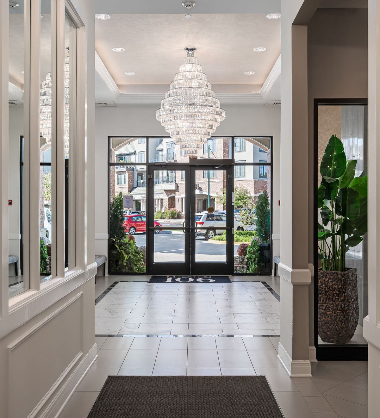 Mission 106 Luxury Apartments pristine entryway with a beautiful chandelier, mirrors lining the walls, and upscaled tile flooring